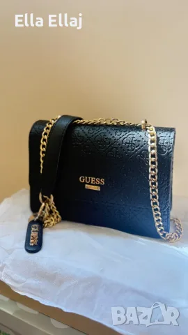 Черна дамска чанта на Guess с релефно лого и златни верижки.
