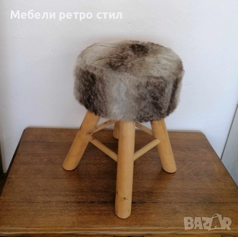 Малка, уютна табуретка  с мека, пухкава седалка с дървени крака в нюанси на сиво и кафяво. 
