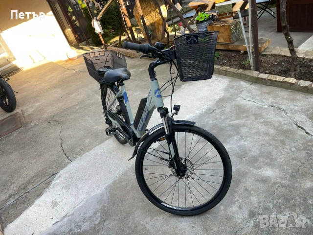 Електрически велосипед Atala с рамка с нисък профил, оборудван с предна кошница и голяма задна товар